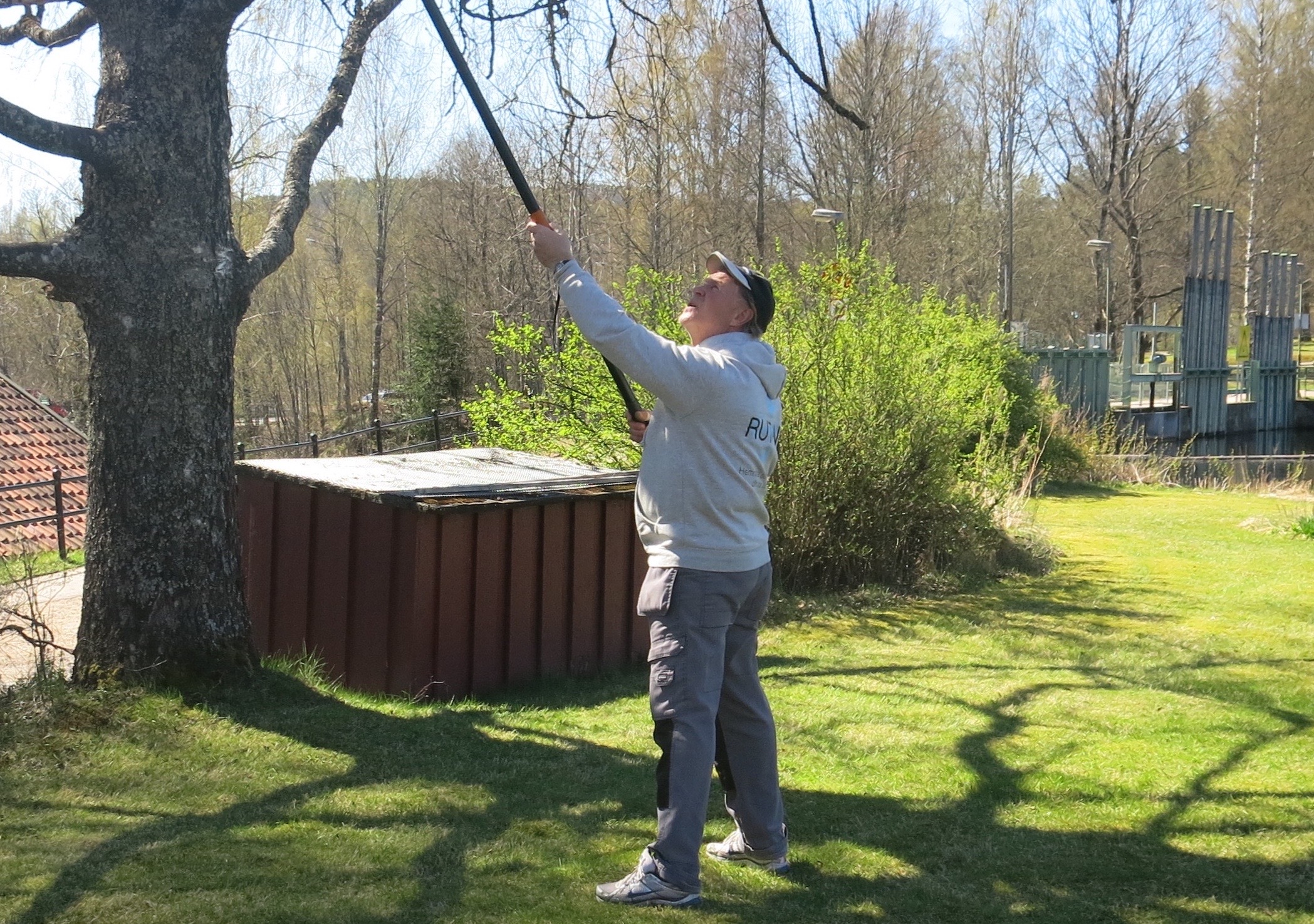 A person in yellow rubber gloves wipes a surface with a blue cloth while holding a spray bottle, dressed in a plaid shirt and jeans.